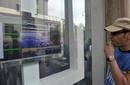 Un manifestante mira la pantalla con los &iacute;ndices del d&iacute;a en la Bolsa de Mil&aacute;n