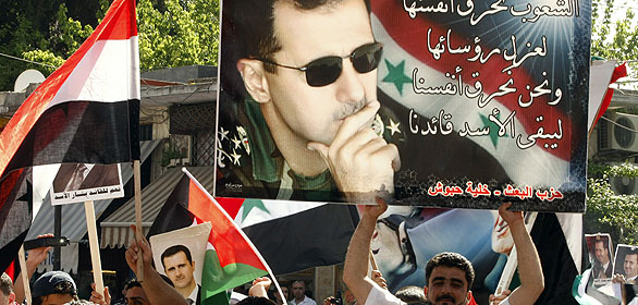 Un manifestante pro-Asad sujeta una pancarta con la imágen del presidente de Siria Un manifestante pro-Asad sujeta una pancarta con la imágen del presidente de Siria