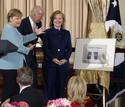 Merkel ense&ntilde;a un obsequio para la secretaria de Estado norteamericana, Hillary Clinton. Es una portada del diario Frankfurter Allgemeine que muestra a las dos pol&iacute;ticas de cintura para abajo.