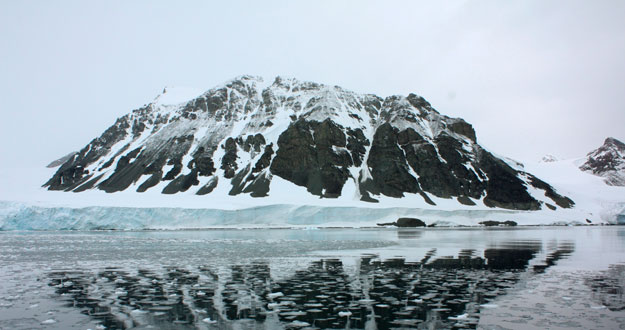 Una monta&ntilde;a se refleja en una bah&iacute;a que antes estaba cubierta por el glacias Sheldon, en la Ant&aacute;rtida.