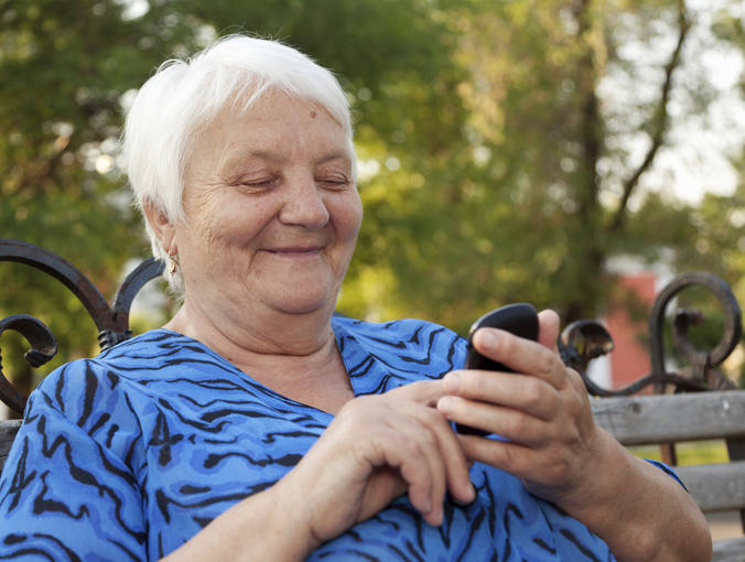 Una mujer mayor usando un tel&eacute;fono m&oacute;vil.