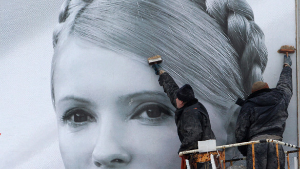 Un grupo de trabajadores municipales colocan un cartel electoral de la candidata Timoshenko.