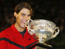 Spains Nadal bites the trophy as he poses after winning his mens singles final match against Switzerlands Federer at the Australian Open