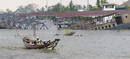 People travel in a boat past destroyed wharves at a port on a swollen river in Yangon