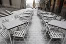 Las sillas y mesas de un caf&eacute; sito en las inmediaciones del Teatro Real, con el Palacio Real al fondo, durante la intensa nevada.