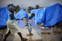 Un niño cruza un charco de agua en medio del fango que dejaron las fuertes lluvias en un campamento improvisado en Cité Soleil en Puerto Príncipe. Un niño cruza un charco de agua en medio del fango que dejaron las fuertes lluvias en un campamento improvisado en Cité Soleil en Puerto Príncipe.
