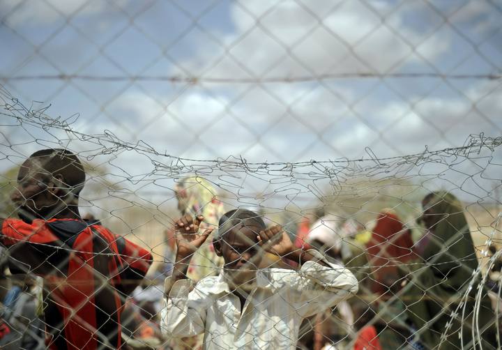 Un ni&ntilde;o mira a trav&eacute;s de una valla c&oacute;mo llegan refugiados al campamento de Al Dadaab, en Kenia.