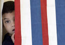 Un ni&ntilde;o se asoma en una cabina de voto en New Hampshire.