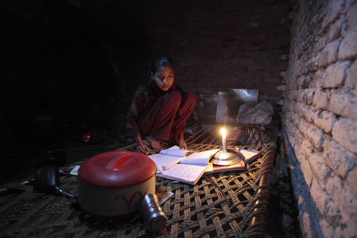 Nor&iacute;n, de 13 a&ntilde;os, usa una vela para estudiar debido a un corte el&eacute;ctrico en un barrio de chabolas de Islamabad