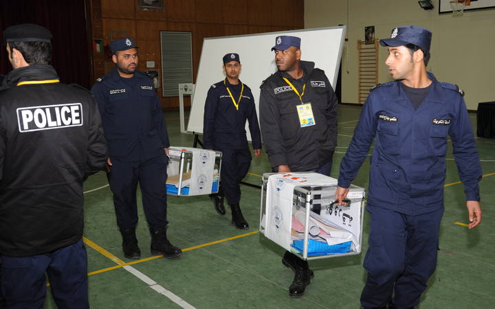 Oficiales de la polic&iacute;a kuwait&iacute; transporta urnas hacia la Asamblea Nacional
