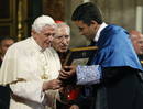El papa Benedicto XVI recibe un regalo durante el encuentro que ha mantenido con representantes del mundo acad&eacute;mico