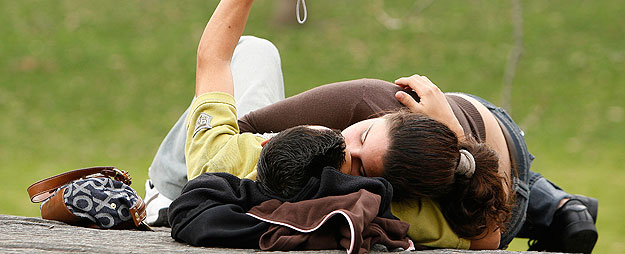 Una pareja de j&oacute;venes se besa en un parque