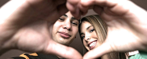 Una pareja dibuja un coraz&oacute;n con sus manos
