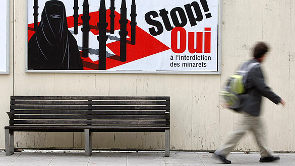 A pedestrian walks past a display advertising the initiative against the construction of new minarets in Switzerland, in Geneva