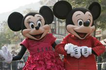 People dressed as cartoon characters Mickey and Minnie greet visitors with their latest Year of the Mouse costumes at Hong Kong Disneyland