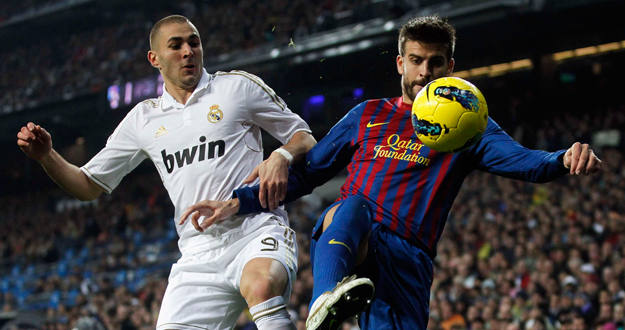 El jugador azulgrana, Gerard Piqu&eacute;, lucha por el control del bal&oacute;n ante Benzem&aacute;.