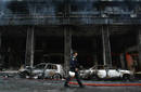 A policeman walks in front of a burnt building following riots in Athens