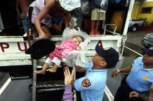 Un polic&iacute;a asistiendo a un bebe durante la evacuaci&oacute;n de un barrio marginal de Manila