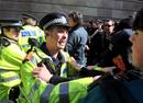 Un polic&iacute;a forcejea con un grupo de activistas anticapitalistas y contrarios al cambio clim&aacute;tico durante una manifestaci&oacute;n cerca del Banco de Inglaterra