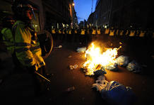La polic&iacute;a protege el fuego ocasionado por algunos manifestantes.