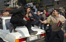 Un polic&iacute;a salta sobre un coche durante la protesta antigubernamental en el centro de El Cairo.