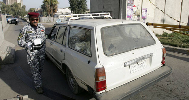 Un polic&iacute;a usa un esc&aacute;ner para inspeccionar un veh&iacute;culo en Bagdad
