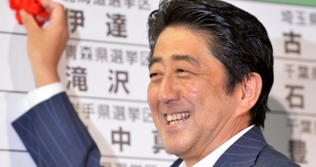 El primer ministro y el presidente del Partido Liberal Democrático (PLD) de Japón, Shinzo Abe, sonríe mientras coloca un papel rojo en el nombre de un candidato del PLD para indicar una victoria electoral en la sede del partido en Tokio.