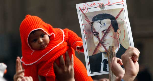 A protester holds up a child in front of a picture of Egypt's President Hosni Mubarak during a protest in Cairo