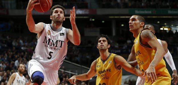El jugador del Real Madrid Rudy Fernández (5) entra a canasta ante los jugadores del Herbalife Gran Canaria Javier Beirán (33) y Nacho Martín (d)