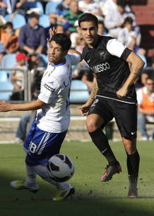 El centrocampista argentino del Real Zaragoza, Lucas Wilchez (i), intenta robar la pelota al defensa del M&aacute;laga CF, Jes&uacute;s G&aacute;mez