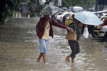 Dos mujeres se protegen de la lluvia en medio de las inundaciones en R&iacute;o.