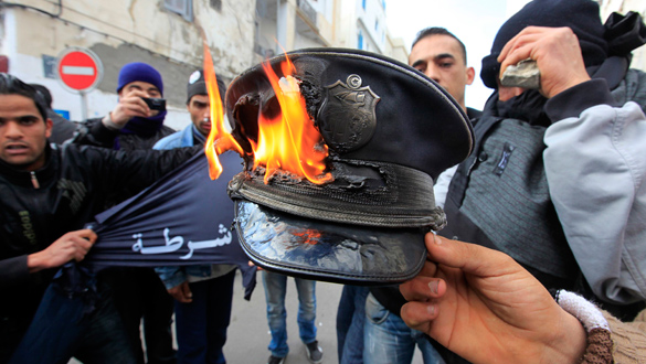 Manifestantes queman un gorro de Polic&iacute;a durante los choques en T&uacute;nez.