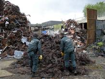 Varios agentes de la Guardia Civil inspeccionan parte de las 160 toneladas de cobre recuperadas en una operaci&oacute;n contra el robo de este metal de los cables telef&oacute;nicos.