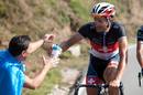 D&aacute;ndole una cantimplora de agua al corredor en plena carrera, entre sonrisas