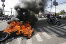 Supporters of Honduras President Zelaya ride on a motorcycle past burning tires near the presidential residency in Tegucigalpa