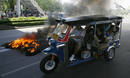 A tuk-tuk passes burning tyres torched by supporters of ousted Thai PM Thaksin in Bangkok
