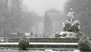 La estatua de la Cibeles con la Puerta de Alcal&aacute; al fondo durante la intensa nevada que cae hoy sobre la ciudad de Madrid y sus alrededores.