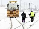 Dos operarios se acercan a una locomotora en las vias cubiertas por la nieve de la estaci&oacute;n de Mataporquera, debido a las intensas nevadas que est&aacute;n cayendo en las zonas interiores de la cornisa cant&aacute;brica.
