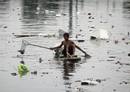 Un ni&ntilde;o filipino usa una tabla para flotar a causa de las inundaciones, en la Ciudad de Las Pinas