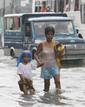 Una madre y su hijo caminan por las calles inundadas de Malab&oacute;n, en el norte de Malnila