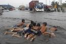 Unos ni&ntilde;os juegan en el agua que ha dejado en las calles el tif&oacute;n Nock-Ten