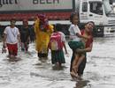 Un ni&ntilde;o lleva a su hermana menor en brazos para cruzar las calles inundadas de Malab&oacute;n, al norte de Manila