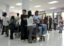 Turistas nacionales y extranjeros esperan su equipaje en el aeropuerto de Utapao, una antigua base militar