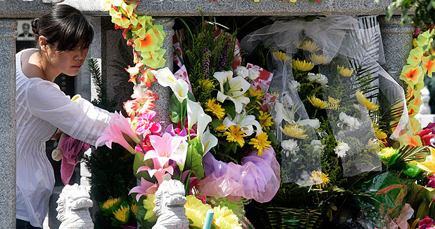 Una mujer deja unas flores en el Parque Memorial del Martirio en Urumqi que recuerda a las v&iacute;ctimas de los disturbios &eacute;tnicos que se produjeron hace un a&ntilde;o.