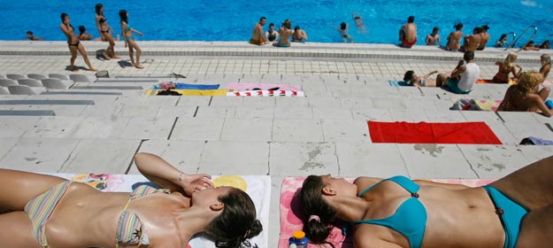 Unas j&oacute;venes toman el sol tranquilamente en una piscina.