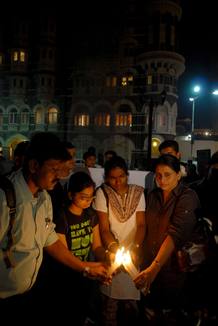 Unas personas encienden velas frente al hotel Taj de Bombay, en la India, durante un acto en memoria de las v&iacute;ctimas de los atentados de Bombay.