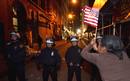 Uno de los miembros de Occupy Wall Street ondea una bandera ante el cord&oacute;n policial