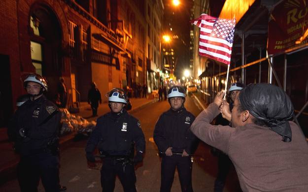 Uno de los miembros de Occupy Wall Street ondea una bandera ante el cord&oacute;n policial
