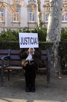 Una mujer de las varias decenas que se han concentrado frente al Supremo para apoyar a Garz&oacute;n, con un cartel de "Justicia" sentada en uno de los bancos.