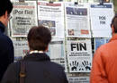 Varias personas leen en un kiosko de San Sebasti&aacute;n las portadas